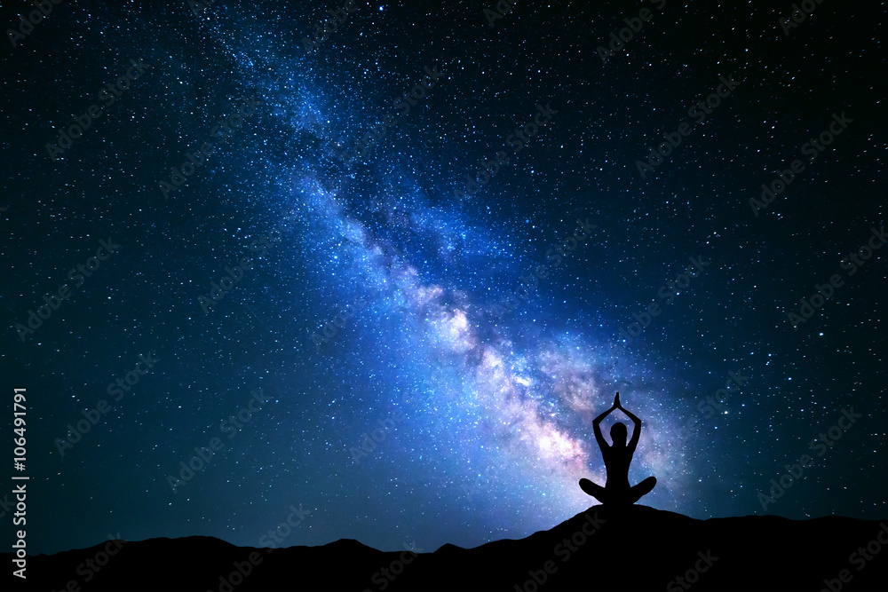 蓝色银河的风景。星星的夜空和一个女孩在空中练习瑜伽的剪影