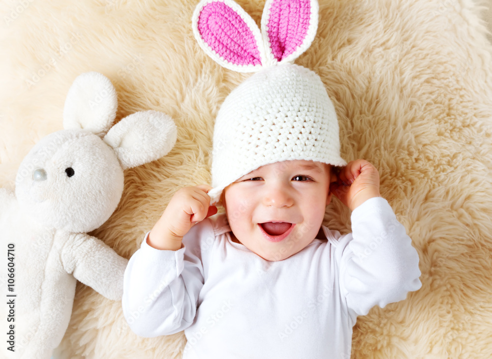 一岁婴儿戴着兔子帽躺在羊羔毛上