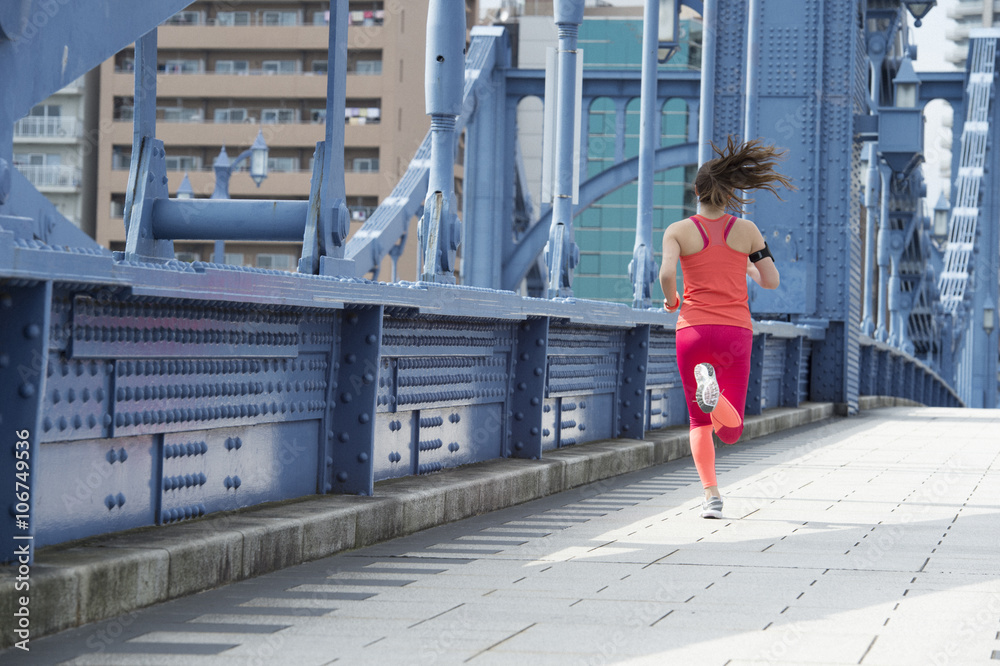 年轻女子穿着运动服在桥上跑步