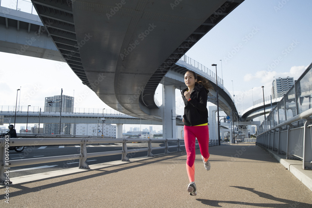 Woman runner is running under overpass