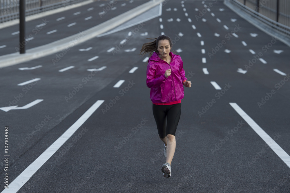 女人穿着运动服在路中央跑步