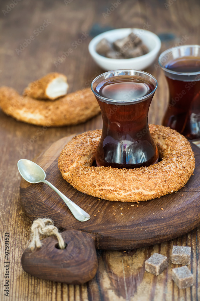 Turkish traditional black tea in a glass and turkish bagel simit on rustic  board over wooden backgr
