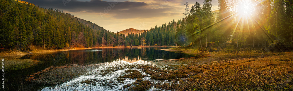 日落时群山松林附近清澈见底的湖泊全景