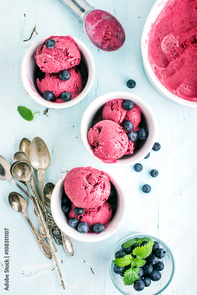 自制蓝莓冰淇淋勺，杯装新鲜浆果和薄荷叶，浅蓝色背面
