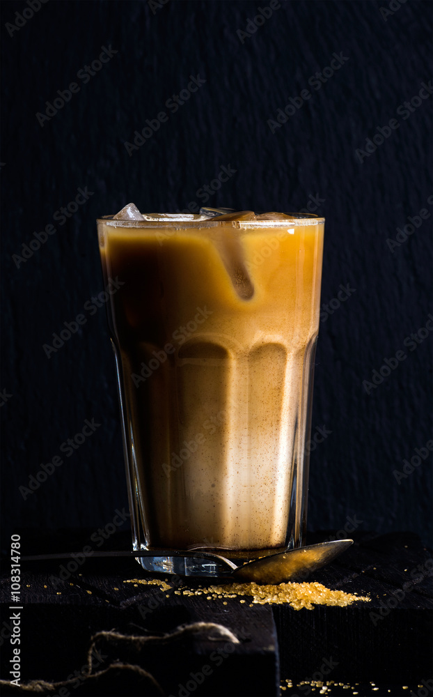 冰咖啡配牛奶，装在高玻璃杯中，莫卡壶，黑色背景