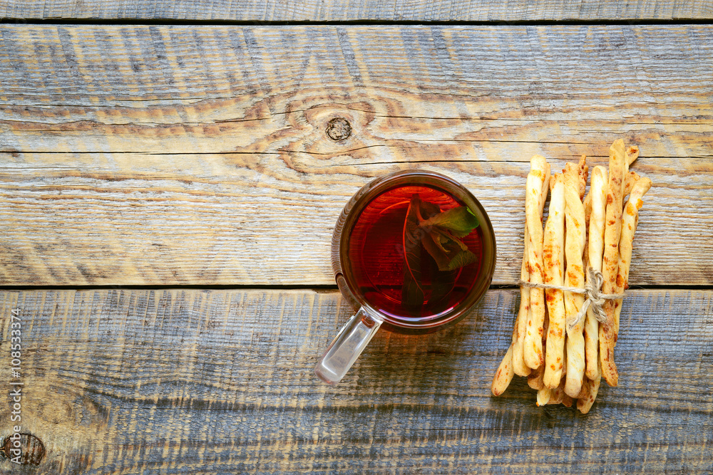 Heap of bread sticks with tea on wooden table