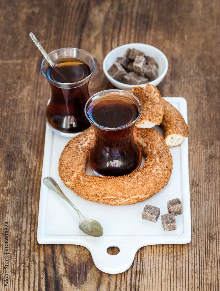 玻璃杯中的土耳其传统红茶和白色陶瓷服务板上的土耳其百吉饼西米特