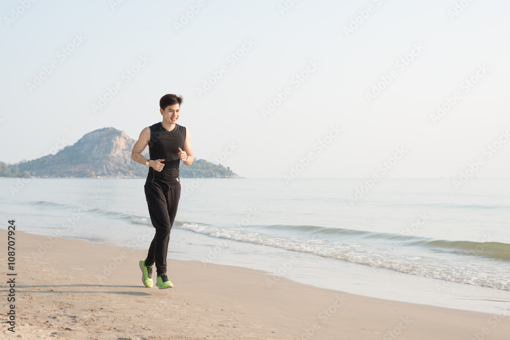 亚洲年轻人早上独自在海滩跑步
