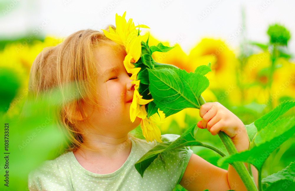 little girl smelling a sunflower