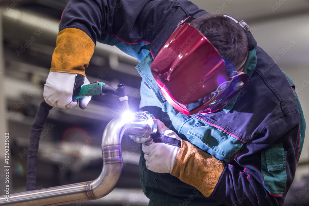 戴着防护面罩的工业工人在钢结构制造车间焊接inox元件