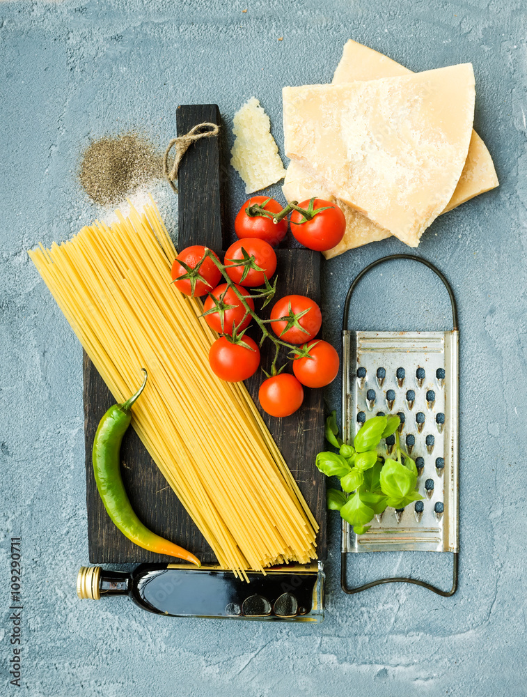 烹饪意大利面的原料。意大利面、帕尔马干酪、樱桃番茄、金属刨、橄榄油