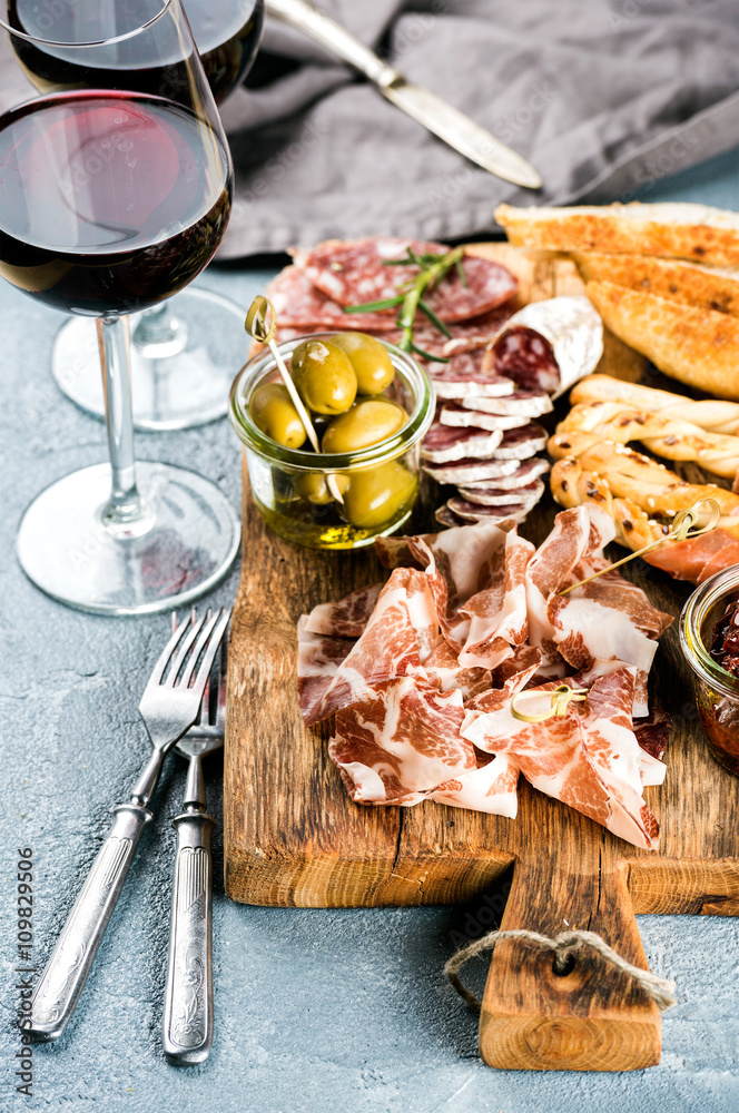 Meat appetizer selection. Salami, prosciutto, bread sticks, baguette, olives and sun-dried tomatoes,