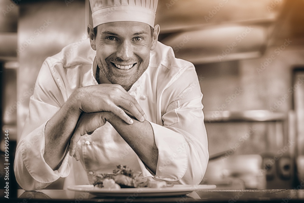 Smiling male chef with cooked food in kitchen