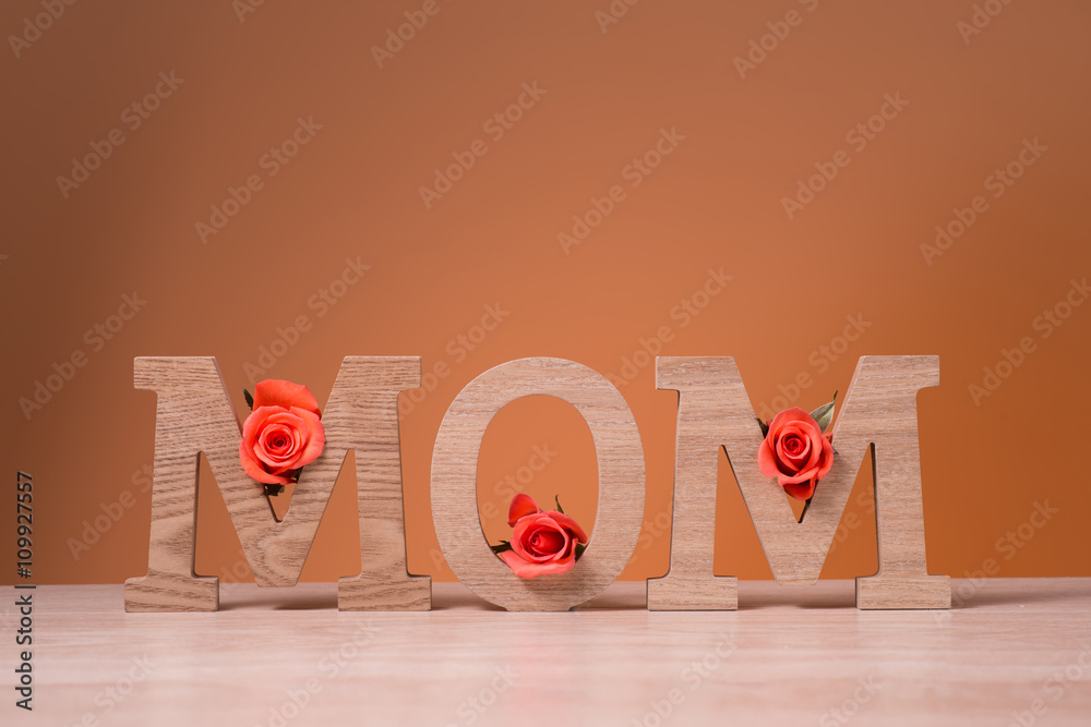 妈妈的字母方块，柔和的背景上有粉红色的玫瑰花。母亲节快乐的概念。