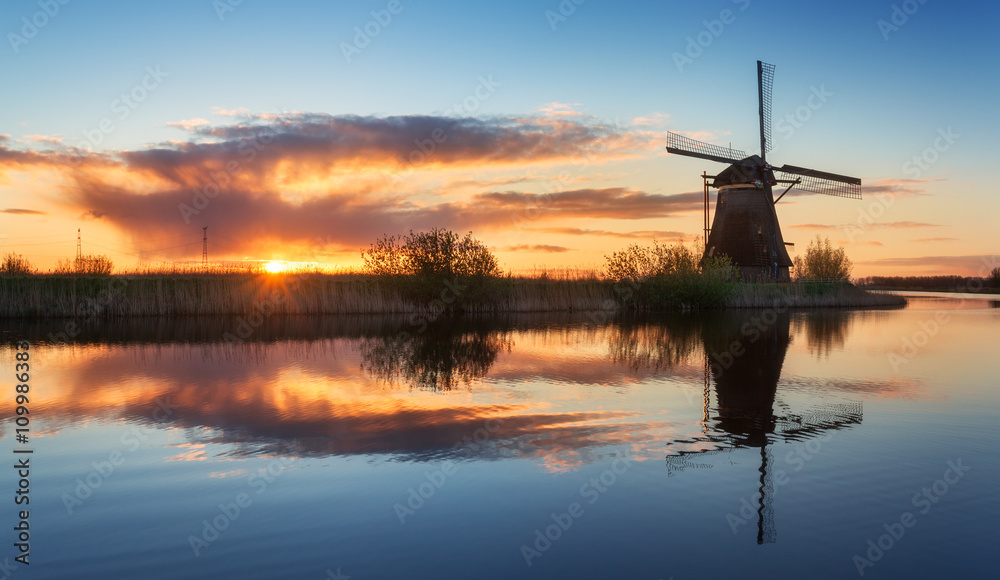 Landscape with beautiful traditional dutch windmills near the water canals with blue sky and clouds 