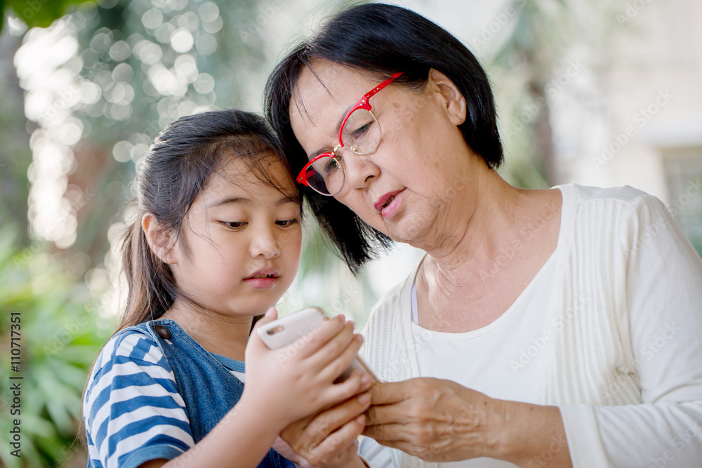 亚洲小女孩和奶奶一起使用手机