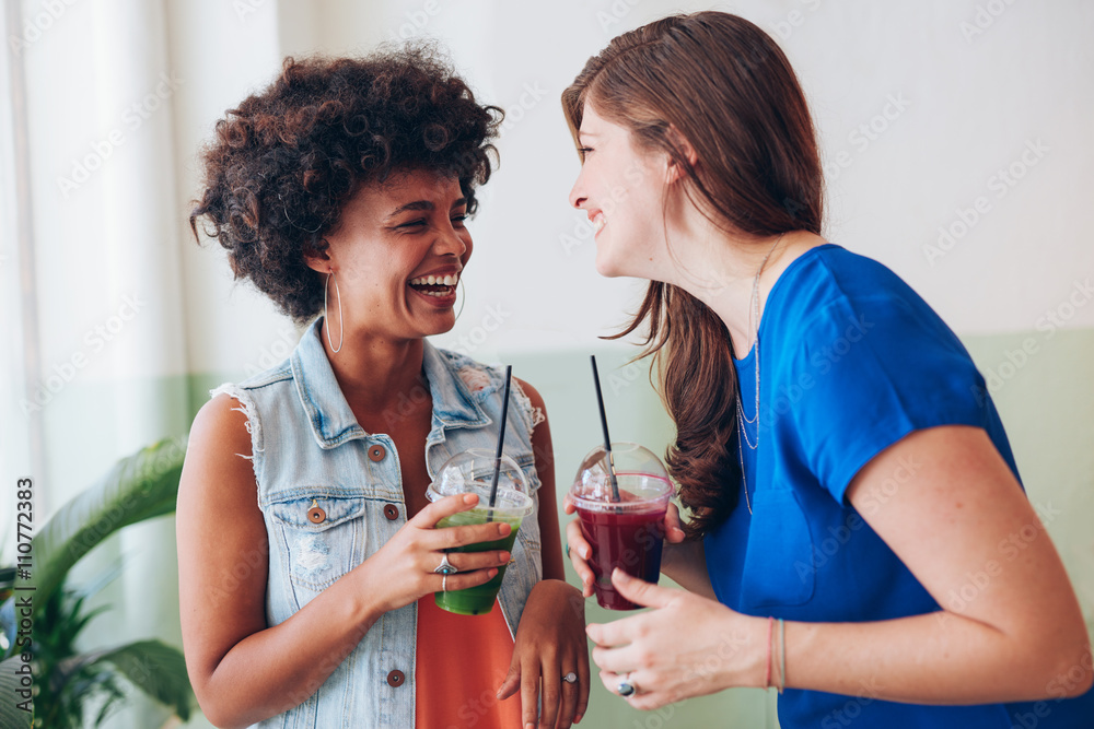 Two young friends having fresh juice and talking
