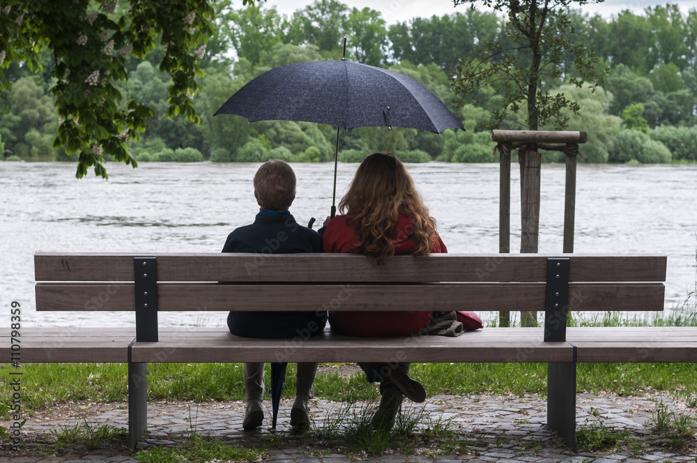 Frauen mit Regenschirm auf einer Bank / Aufnahme zeigt zwei Frauen, unterschiedlichen Alters sitzend