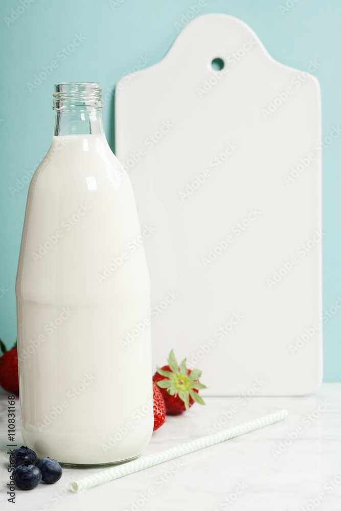 一瓶牛奶、浆果、白色陶瓷餐盘和纸