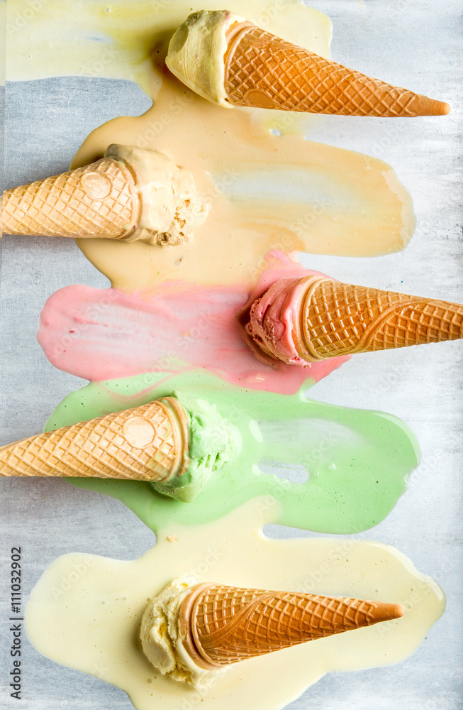 不同口味的彩色冰淇淋筒。融化的勺子。俯视图，钢金属背景。