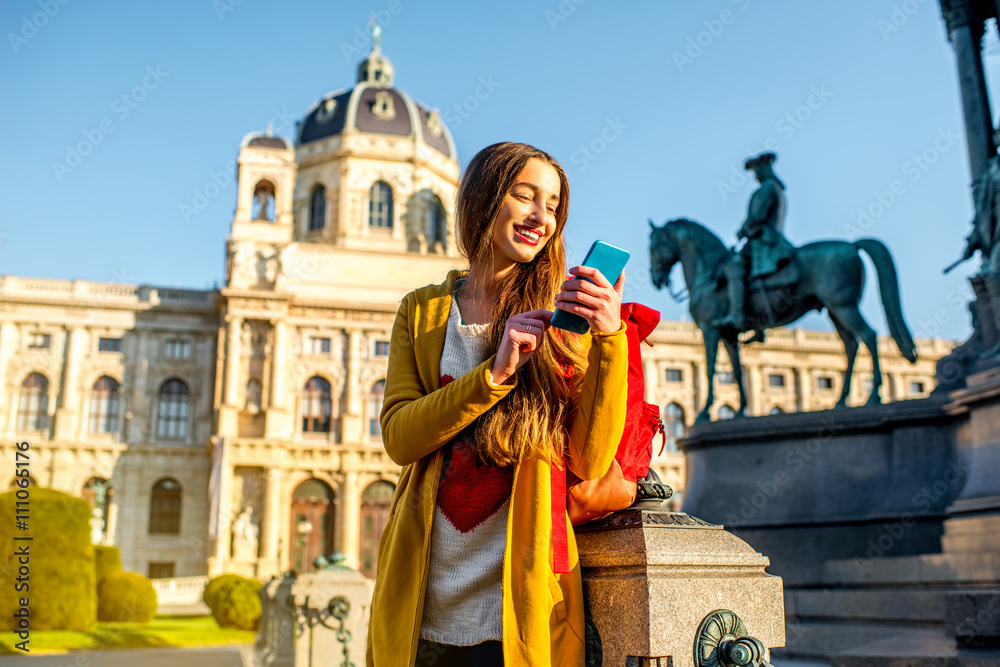 维也纳自然历史博物馆附近的玛丽亚·特蕾莎广场上年轻的女游客拿着智能手机