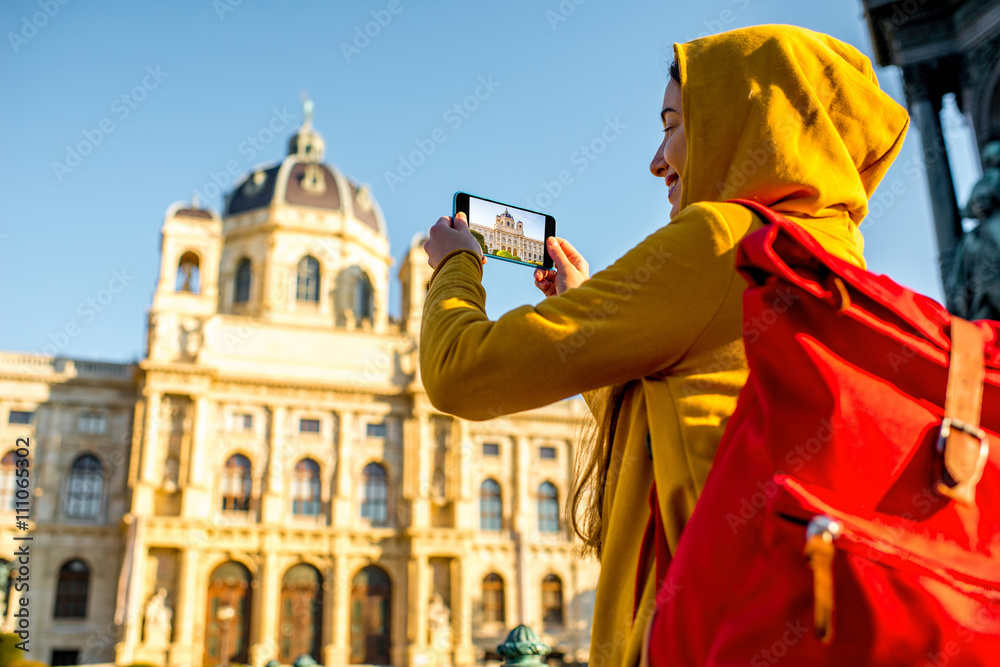 年轻女性游客用智能手机拍摄维也纳自然历史博物馆。