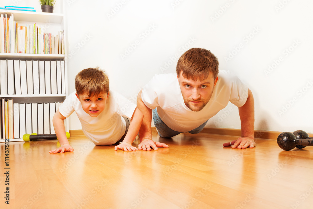 父亲和儿子在家锻炼，做俯卧撑