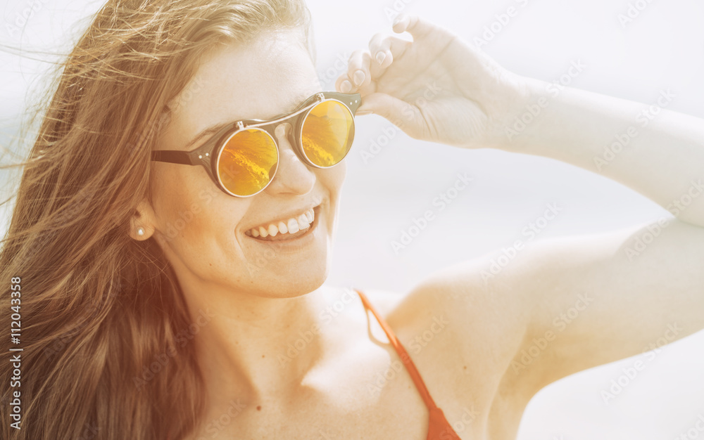 Young woman on the beach in hot summer sun light