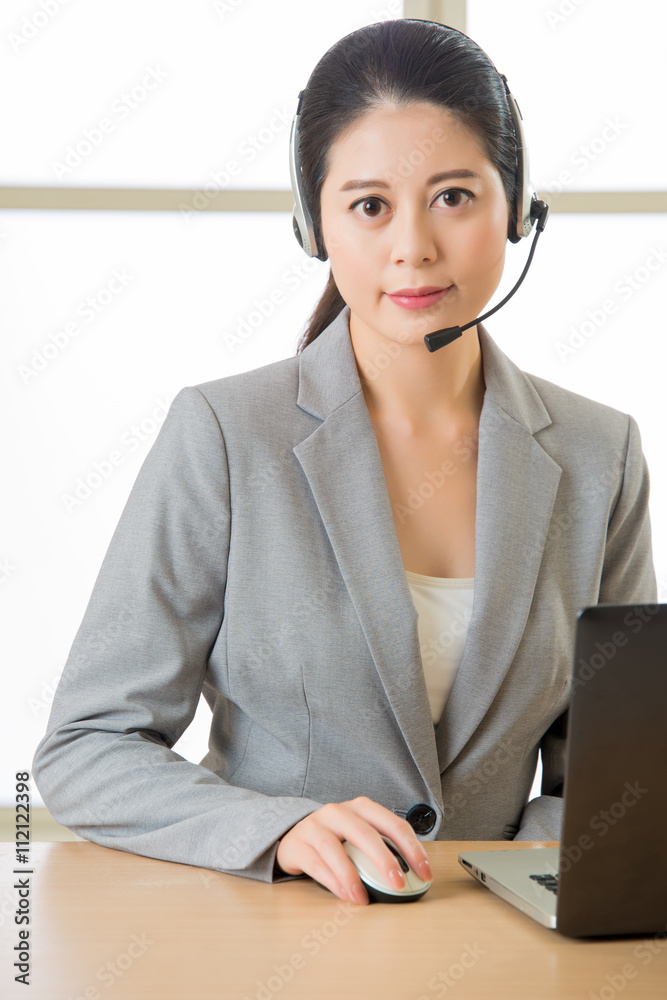 Smiling Asian woman with a headphone and working on laptop