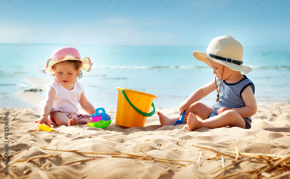 坐在海滩上的女婴和男婴