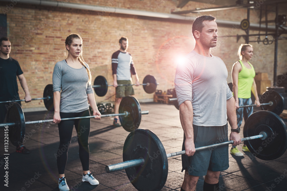 Strong man leading group in barbell exercises