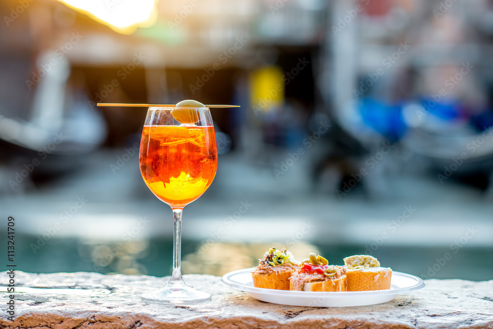 Spritz Aperol drink with venetian traditional snacks cicchetti on the water chanal background in Ven