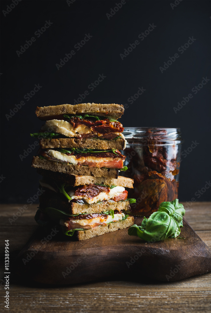 Caprese sandwich or panini. Whole grain bread, mozzarella, cherry and dried tomatoes, basil