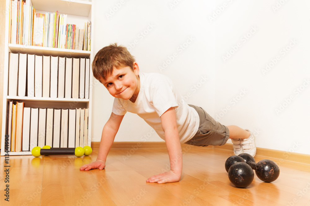 Kid boy working out on the floor, doing push-ups