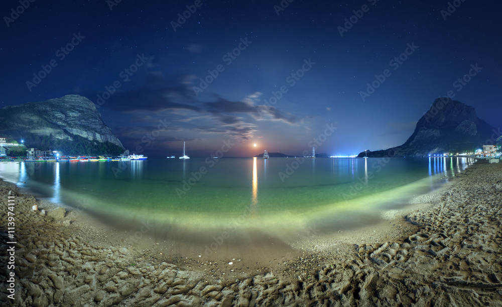 Beautiful night landscape at the seashore with yellow sand, full moon, mountains and lunar path. Moo