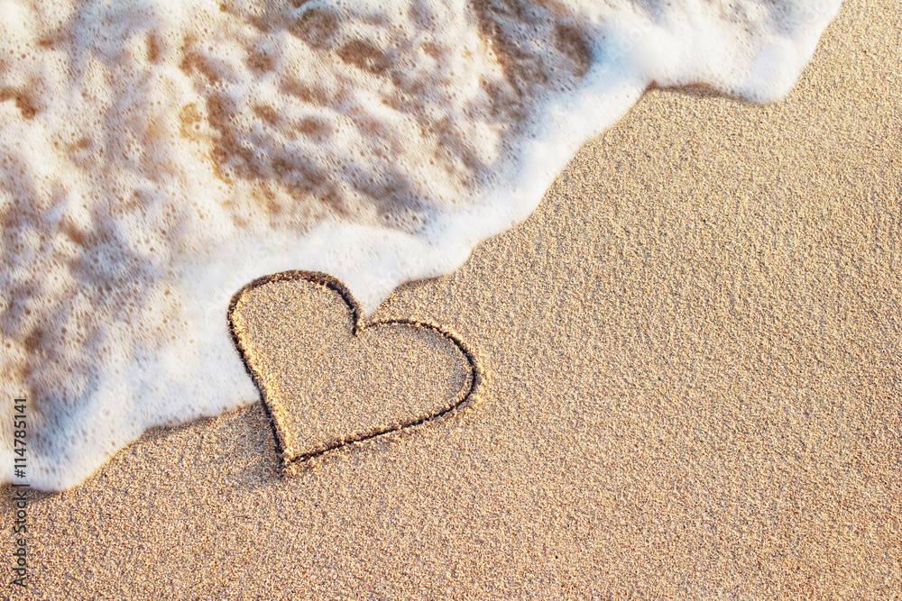 在海浪柔和的沙滩上手写的心形符号