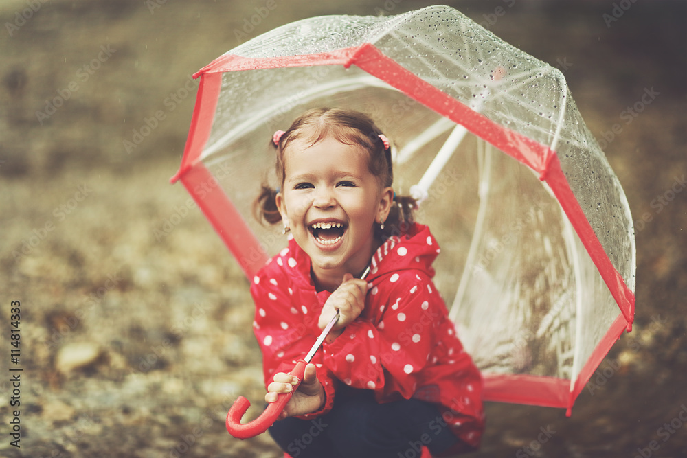 快乐的小女孩在雨中撑着伞大笑
