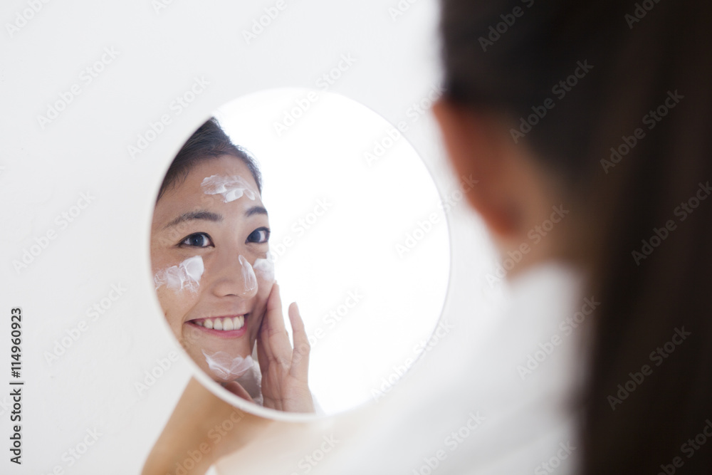 女人照镜子时脸上涂着奶油