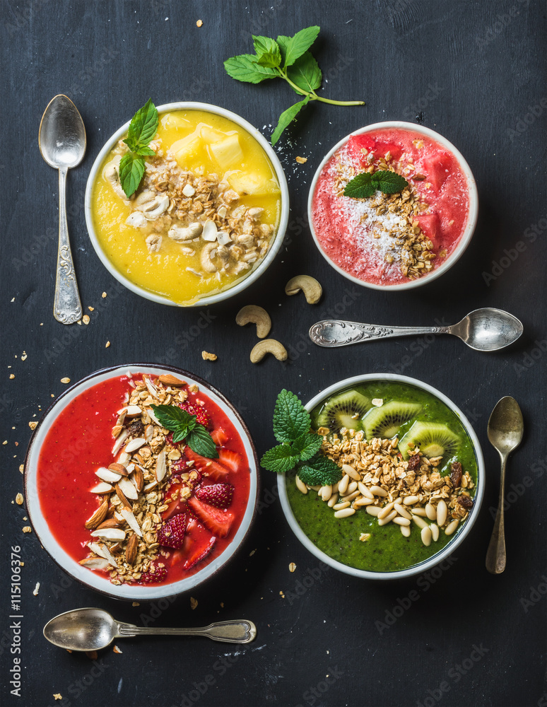 健康的夏季早餐概念。五颜六色的水果奶昔碗，配坚果、燕麦格兰诺拉麦片和薄荷叶