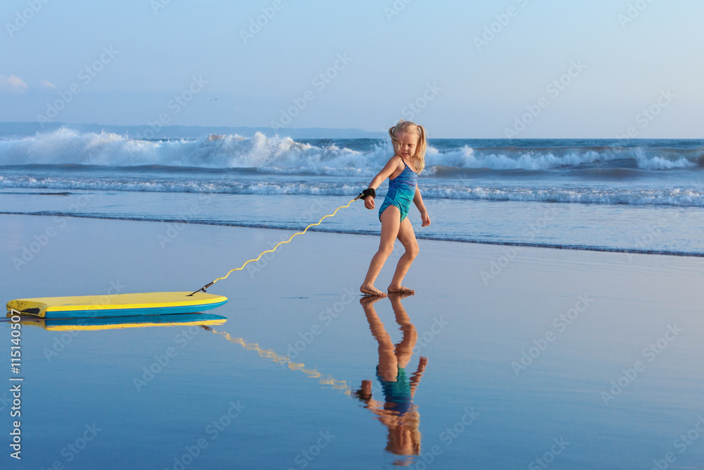 小女婴-带着冲浪板的年轻冲浪者在海滩上玩得很开心。家庭生活方式，人们超越