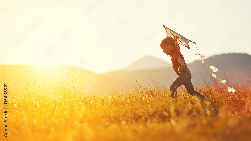 快乐的小女孩带着风筝在夏天的草地上奔跑