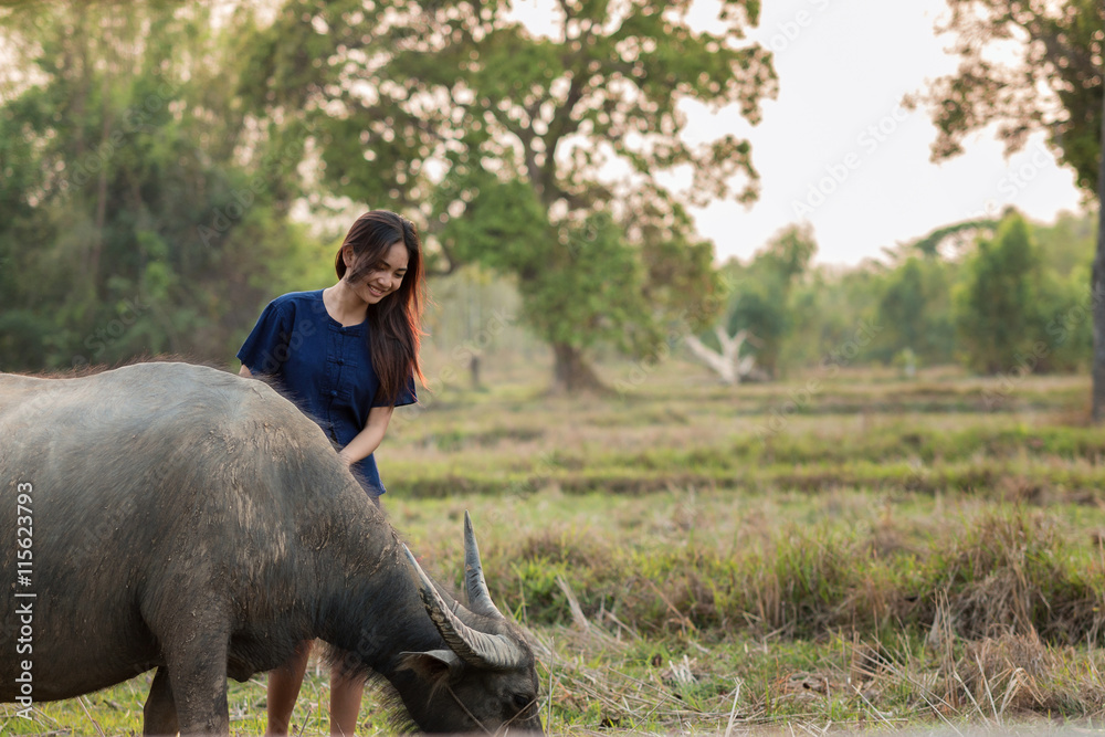 泰国女孩在农场里撑着伞和她的水牛。