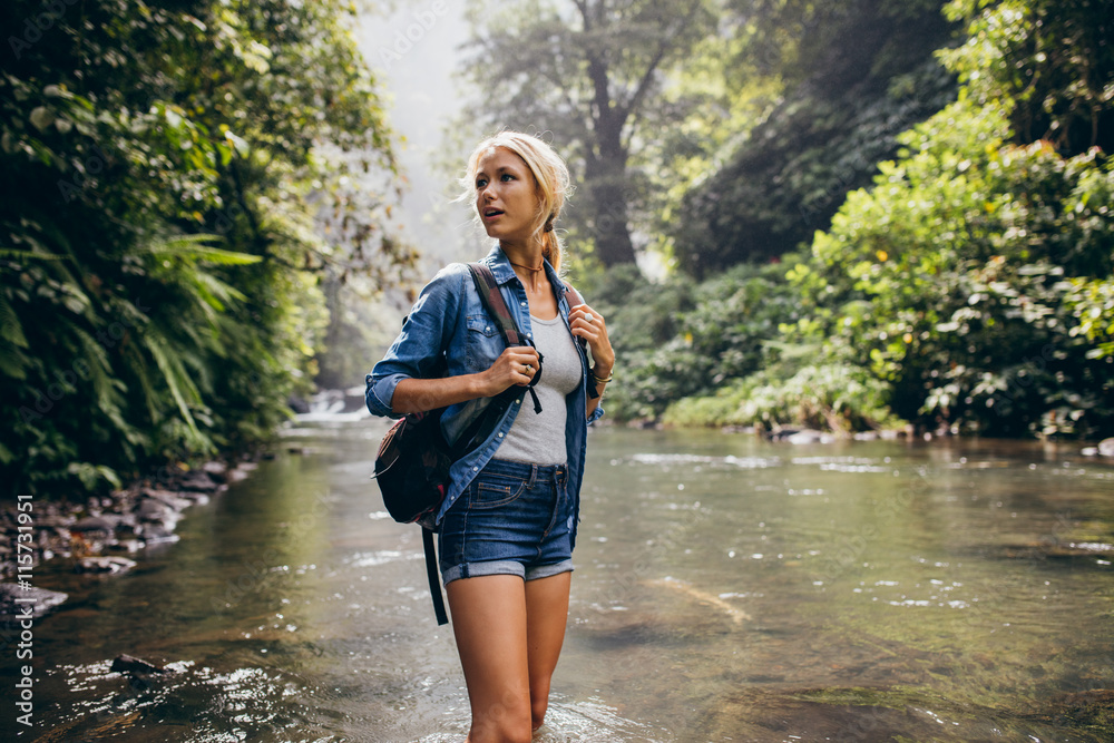 Beautiful woman with backpack standing by the creek
