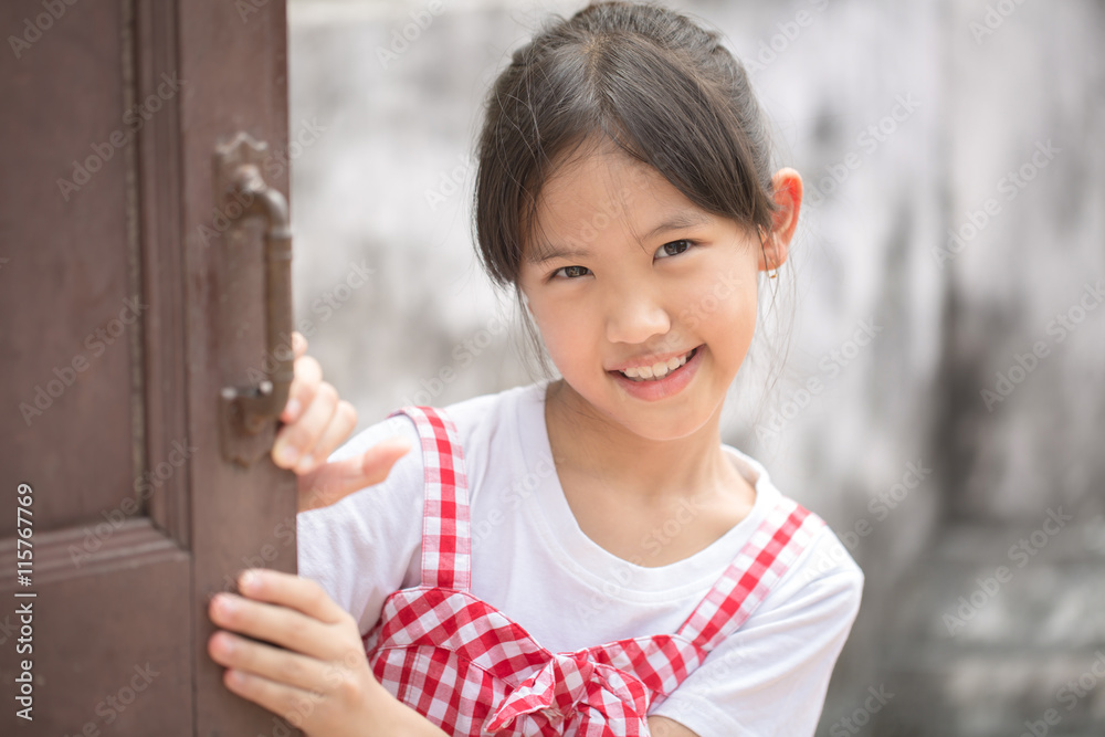 可爱的年轻亚洲女孩画像隐藏在木门后面玩耍