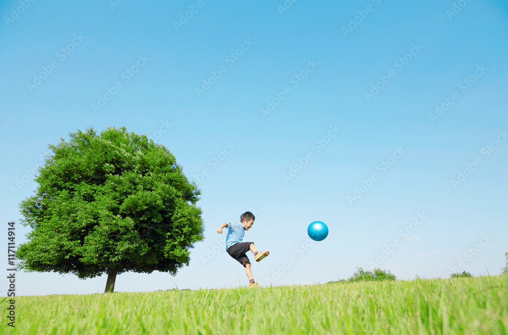広場でボールで遊ぶ男の子
