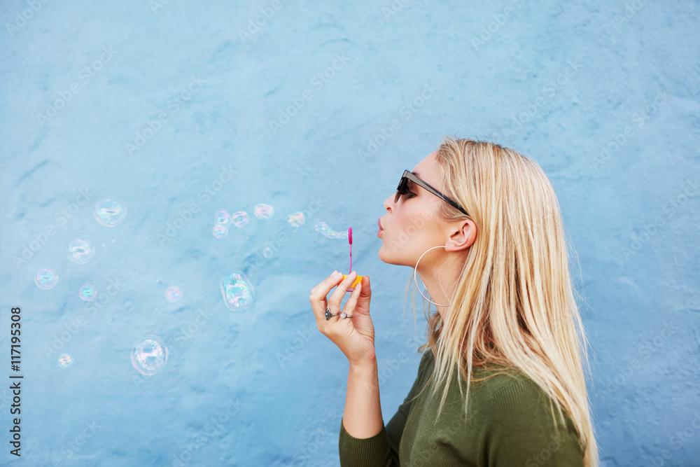 Young beautiful woman blowing soap bubbles