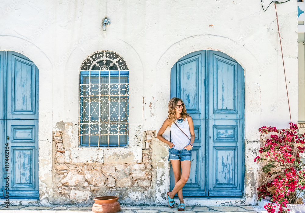 年轻的金发女人在典型的希腊传统小镇上，在G卡斯特洛里佐岛上有五颜六色的建筑