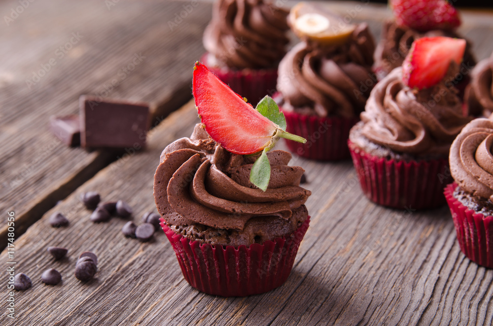 Chocolate cupcakes with strawberry and chocolate on a wooden table.