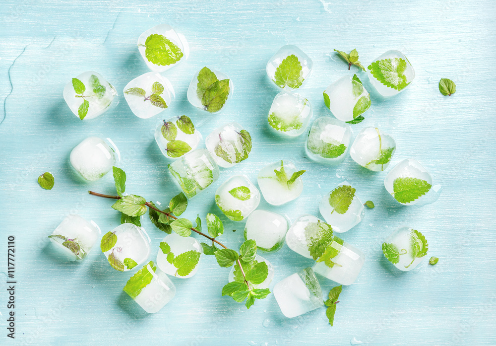 Ice cubes with frozen mint leaves inside on blue Turquoise background, top view, horizontal composit
