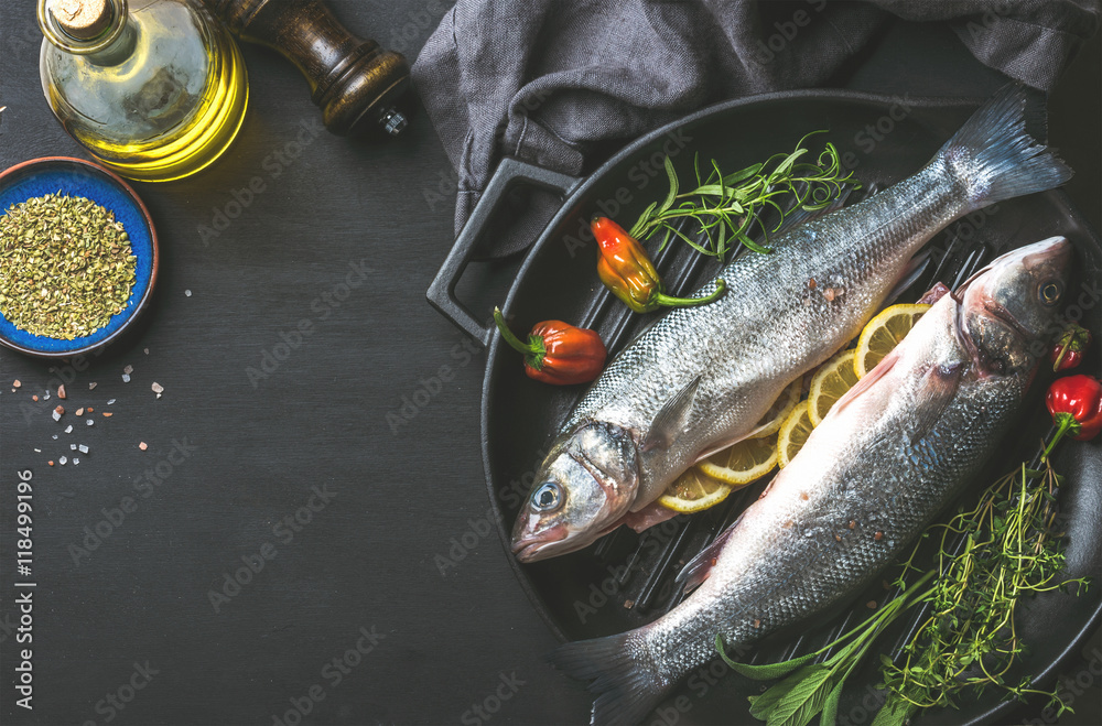 烹饪健康鱼类晚餐的食材。生的未煮熟的鲈鱼配橄榄油、香草和香料